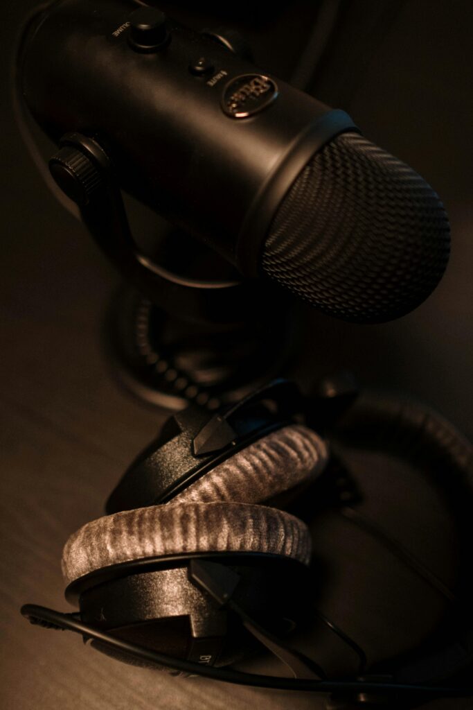 Close-up of a black microphone and headphones on a dark surface, ideal for podcasting or studio work.
