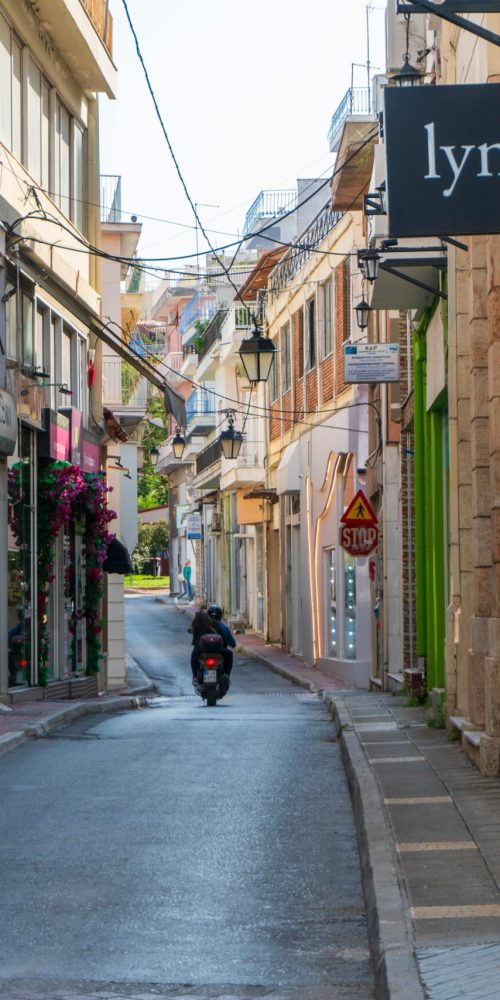 A picturesque narrow street lined with shops and a motorcyclist in an urban setting.